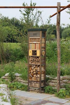 an outdoor firewood storage unit in the middle of a garden with lots of logs