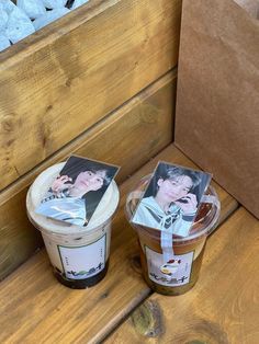 two ice creams sitting next to each other on a wooden bench with pictures in them