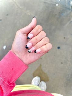 a woman with black and white nail polish holding her hand up to the camera while sitting down