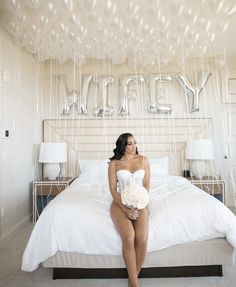 a woman sitting on top of a bed under balloons