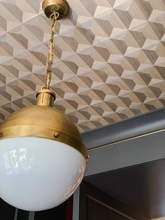 a light fixture hanging from the ceiling in a room with geometric wallpaper on it