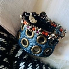 a close up of a blue bracelet on a white cloth with metal rings and beads