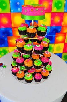 cupcakes are stacked on top of each other in front of a brightly colored backdrop