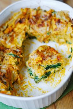 a casserole dish with spinach and cheese in it on a wooden table