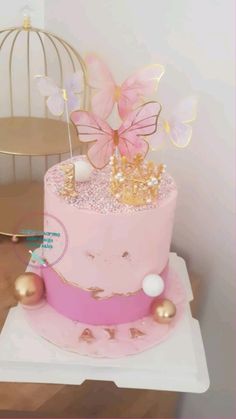 a pink cake with gold decorations on top and a birdcage in the background