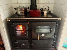 an old fashioned wood burning stove with pots and pans on top