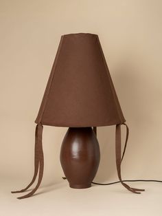 a lamp with a brown shade on it and a cord attached to the bottom of the lamp