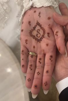 a bride and groom holding their hands with henna tattoos on it's palms