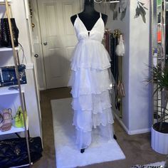 a white dress on display in front of a closet with handbags and purses