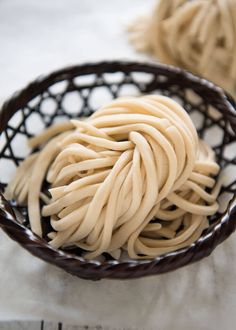 a bowl filled with noodles sitting on top of a white cloth covered table next to two balls of yarn