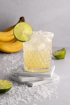 a drink with limes and sugar on the table next to bananas, salt and pepper