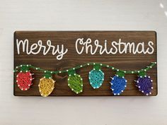 a wooden sign that says merry christmas with string lights