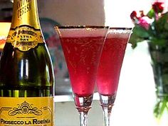 two glasses filled with pink liquid next to a bottle of wine on a counter top