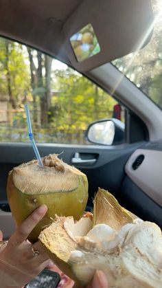 a person holding up a coconut in the back seat of a car