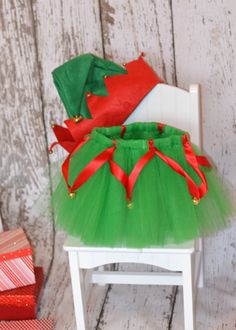 a green tutu skirt sitting on top of a white chair next to christmas presents