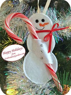 a snowman ornament hanging from a christmas tree with candy canes in it