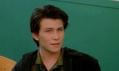 a young man sitting in front of a green wall