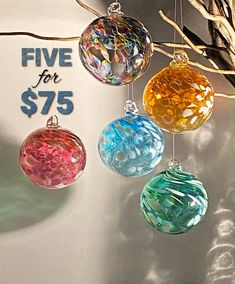 five glass ornaments hanging from a tree branch with the price for $ 75 on it