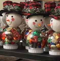 three snowmen with hats and candy in front of each other on a shelf next to christmas decorations