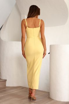 a woman in a yellow dress is standing on the floor with her back to the camera