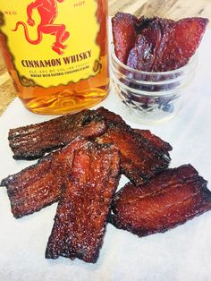 some ribs are next to a bottle of cinnamon whiskey