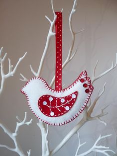 a red and white bird ornament hanging on a tree branch with polka dots