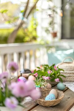 a wooden table topped with baskets filled with flowers and easter eggs on top of it