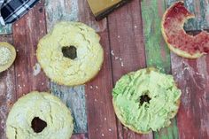 three doughnuts with guacamole and other toppings on a wooden table