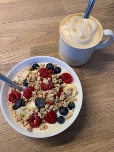 a bowl of cereal with berries and yogurt next to a cup of coffee