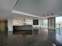 an empty living room and kitchen with large windows overlooking the cityscape at night