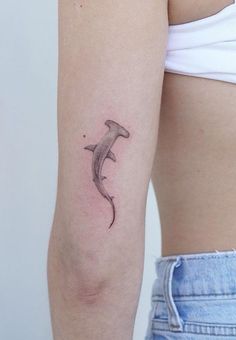 a woman's arm with a small dolphin tattoo on it