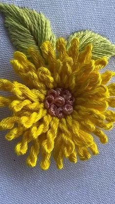 a yellow flower with green leaves is on a blue cloth fabric background, close up