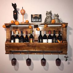 a wooden shelf filled with bottles of wine and two owls sitting on top of it