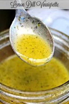 a spoon full of lemon dill vinaiette is being held over a jar