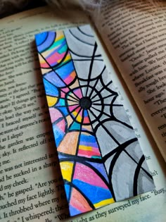 an open book with a spider web on it and the pages are painted multicolored