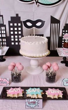 a table topped with cake and cupcakes on top of a white table cloth