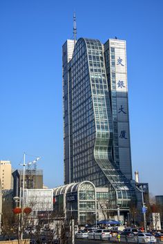 a very tall building sitting in the middle of a city with lots of cars parked around it