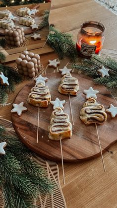 some cookies are sitting on a wooden board with christmas decorations around them and candles in the background