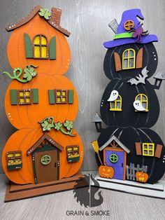 two halloween decorations made to look like pumpkins and houses with bats on them are sitting next to each other