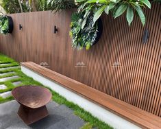 a wooden bench sitting next to a lush green garden on the side of a building