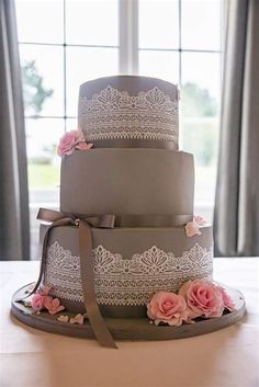 a three tiered cake with lace and flowers on it