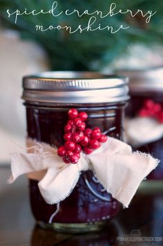 two jars filled with jam sitting on top of a table next to a christmas tree