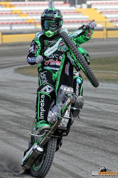 a man riding on the back of a motorcycle down a race track with his arms in the air