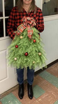 a woman wearing a green christmas tree skirt and black boots, standing in front of a door