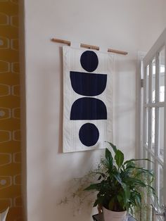 a potted plant sitting on top of a wooden table next to a wall hanging