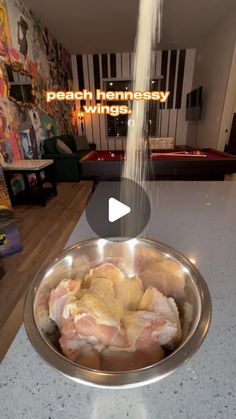 a metal bowl filled with meat sitting on top of a counter next to a wall