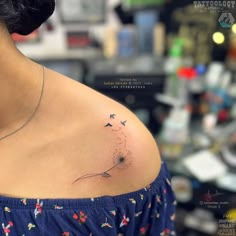 a woman's shoulder with a dandelion tattoo on the left side of her upper arm