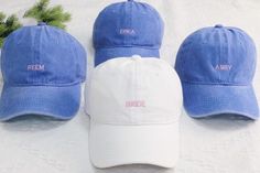 three blue and white hats sitting on top of a bed next to a pine branch