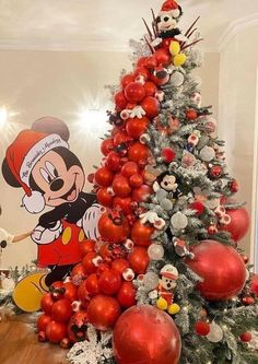 a christmas tree decorated with red and silver ornaments, mickey mouse ornament on top