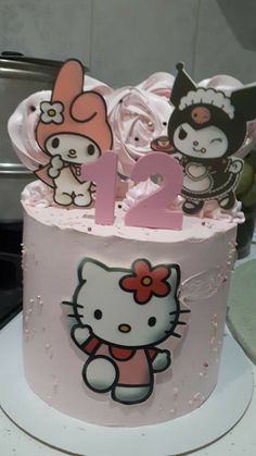 a hello kitty birthday cake is decorated with pink icing and white fondant decorations